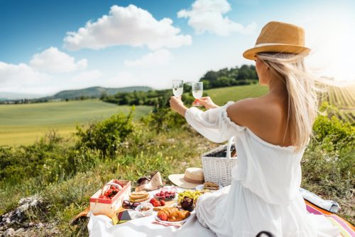 Radość. kobieta na pikniku trzyma w dłoniach dwa kieliszki do szampana